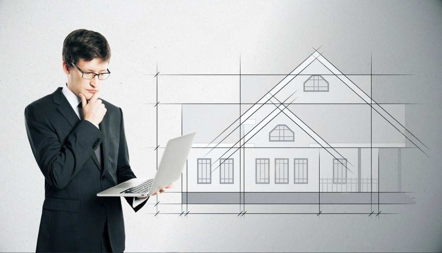 Security consultant reviewing a villa protection project on a laptop next to a house blueprint